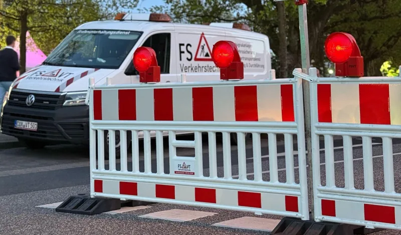 Einsatzfahrzeug von FSVT Verkehrstechnik hinter Absperrschranken mit roten Signalleuchten